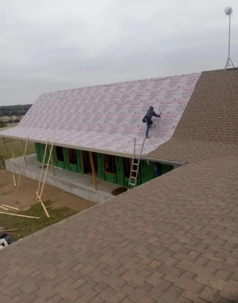 Worker preparing underlayment for a metal roof installation in Channelview